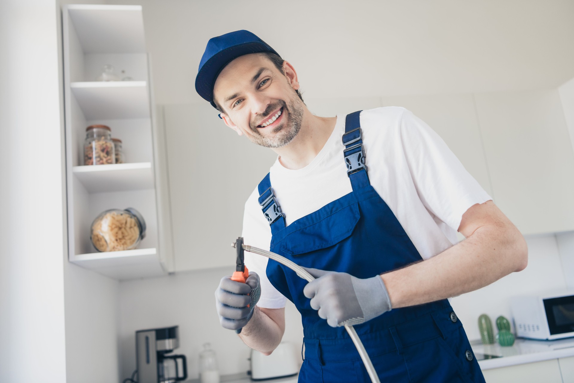 Smiling handyman in a modern kitchen working on appliance installation with professional tools and expertise