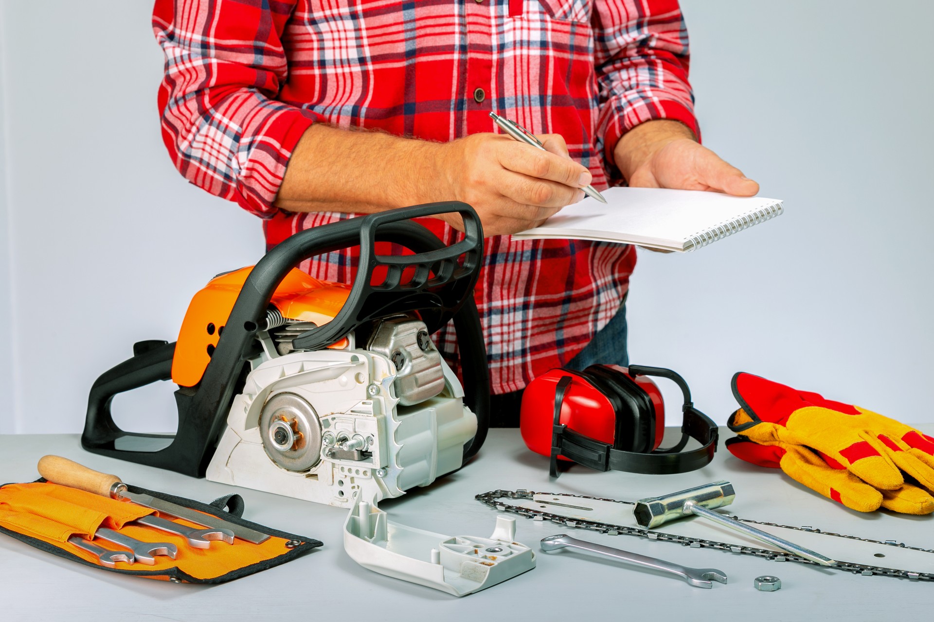 Man with diary notebook a pen in repair shop. Repair of chainsaws,gasoline powered tools.