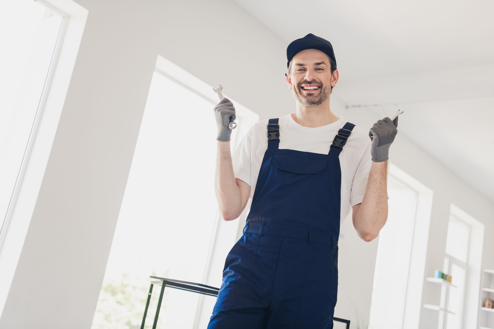 Confident handyman in uniform ready for home renovation with tools in bright modern apartment interior